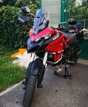 Red and black Ducati motorcycle parked near a green gate.