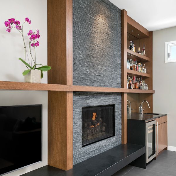 Modern living room with a stone fireplace and built-in bar area.