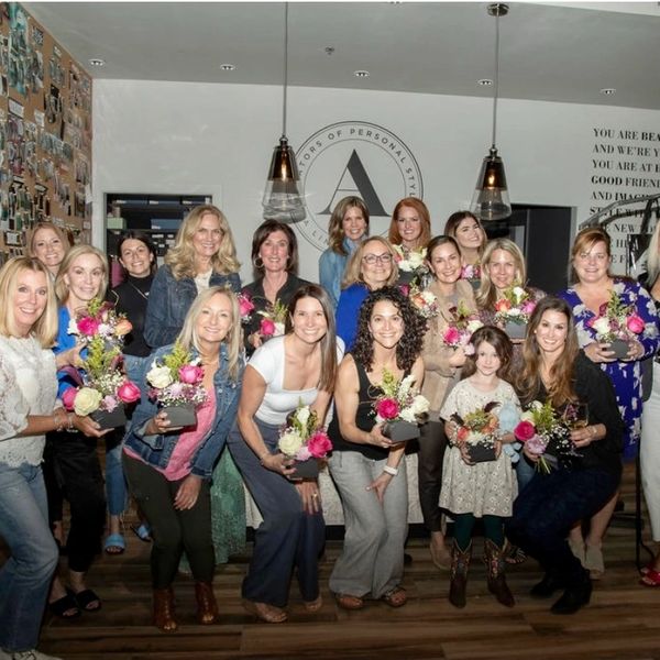 Group of women holding flower arrangements indoors.