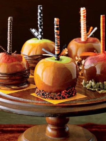 Assorted gourmet caramel apples with decorative sticks.