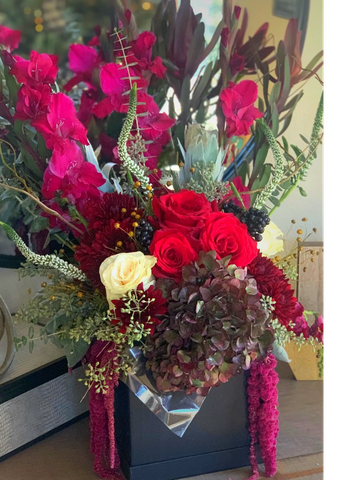 Vibrant mixed flower arrangement in a black box.