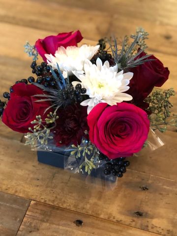 Red roses and white flowers bouquet on wooden table.