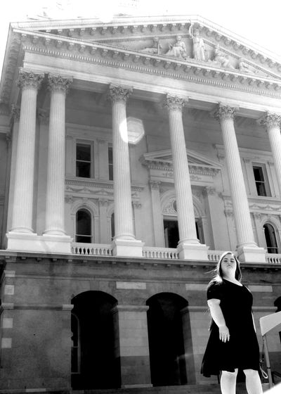 Nicole Adler standing in front of the California State Capitol building wearing a black dress. 