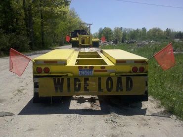 A yellow 'Wide Load' trailer on a rural road.