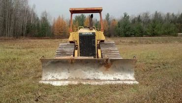 Front view of a bulldozer on a grassy field.