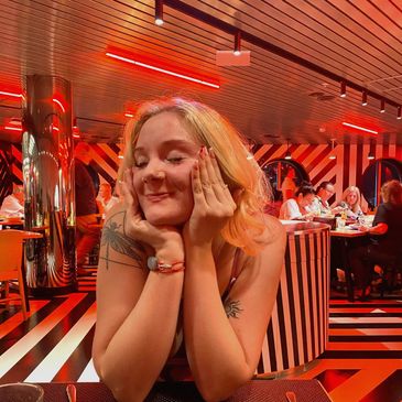 A woman smiles with closed eyes in a vibrant, striped restaurant setting.