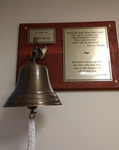 A commemorative brass ship bell mounted on a wooden plaque.