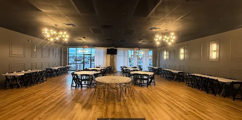 Spacious event room with wooden floors and round tables.