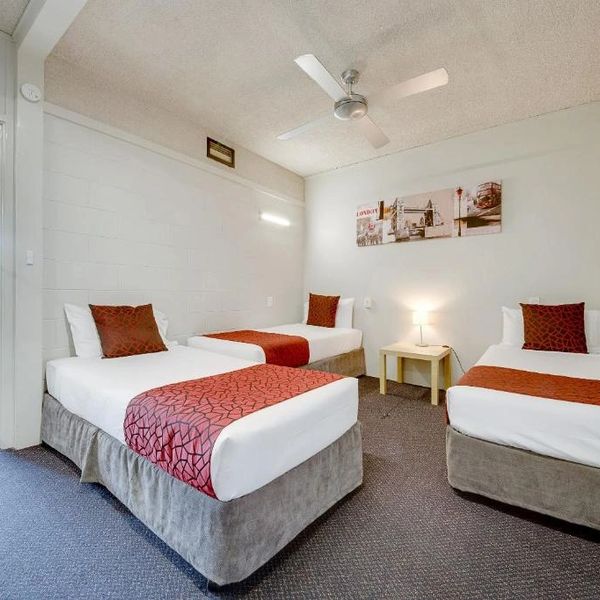 Clean hotel room with three single beds and modern decor.