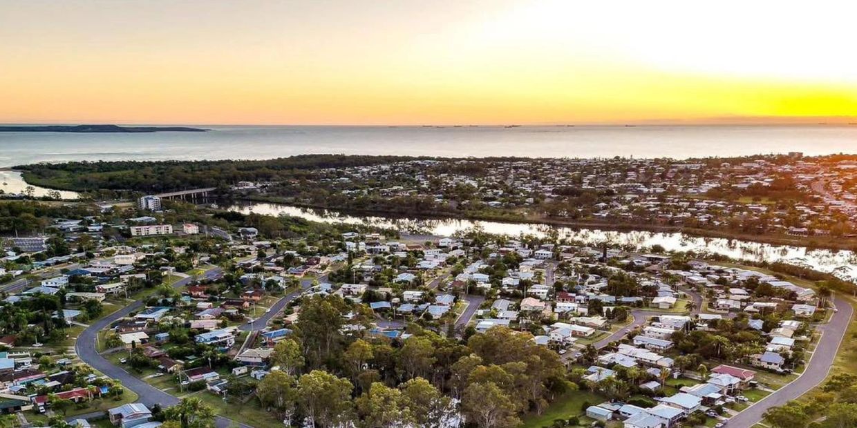 A coastal town at sunset with houses and a river.