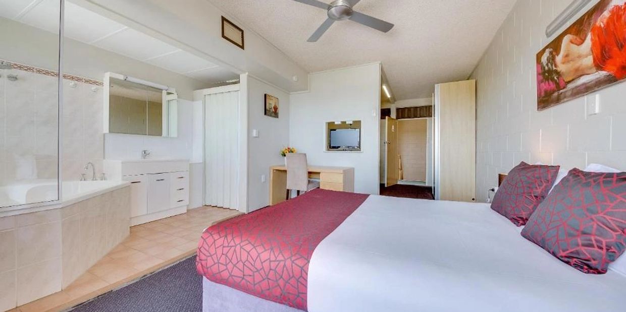 Modern hotel room with a bed, desk, and attached bathroom.