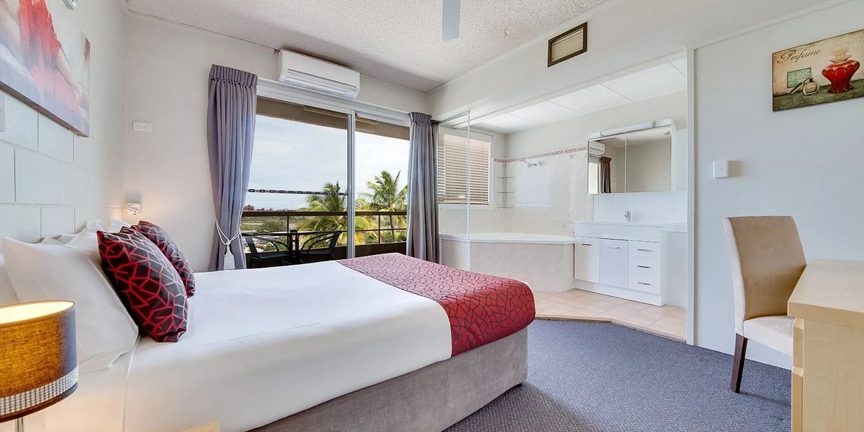 Modern hotel room with a bed, balcony, and open bathroom area.