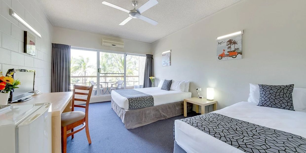 Bright hotel room with two beds, balcony, and modern decor.