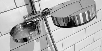 Close-up of shower fixtures on tiled wall.
