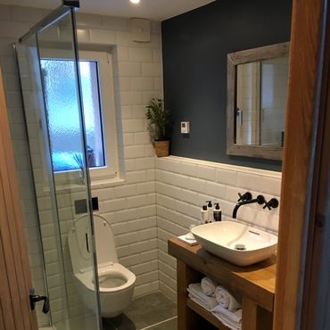 Small modern bathroom with white tiles and wooden accents.