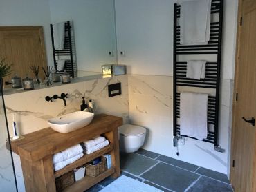 Modern rustic bathroom with wooden vanity and white fixtures.