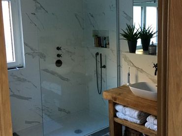 Modern bathroom with glass shower and wooden vanity.