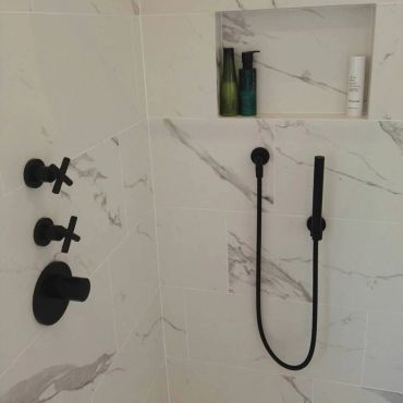 Modern bathroom shower controls and built-in shelf.