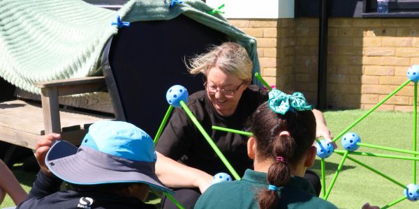 Adult engaging with children outdoors.