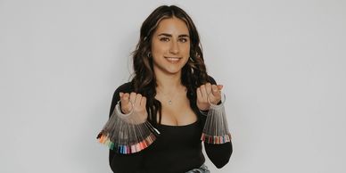 Woman holding two sets of nail polish color samples, smiling.