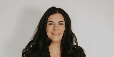 Smiling woman with long dark hair against a plain background.