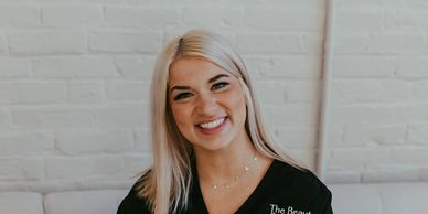 Smiling young woman with blonde hair sitting indoors.