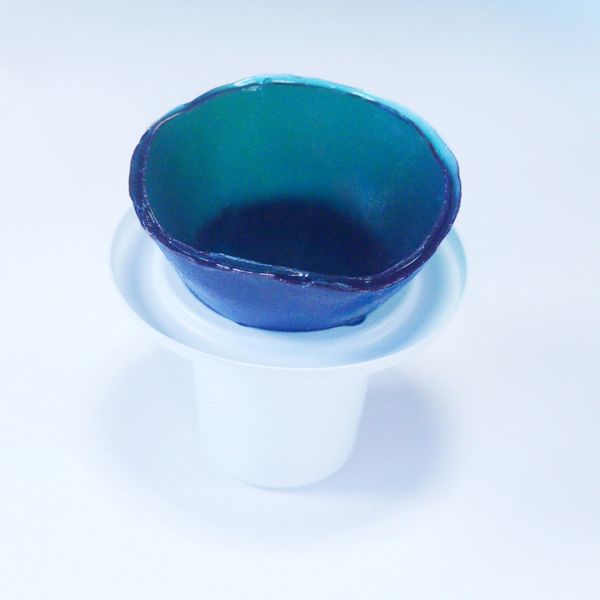 Blue ceramic bowl placed on a white plastic container against a white background.