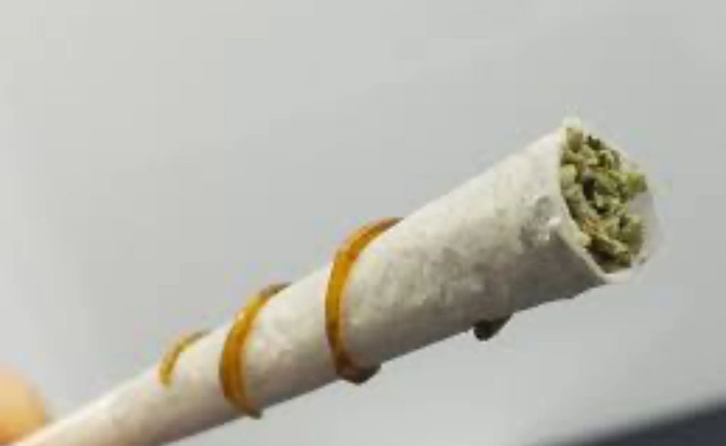 Close-up of a rolled joint with a rubber band wrapped around it.