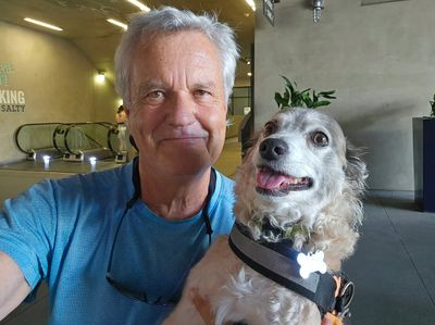 Man taking a selfie with a happy dog indoors.