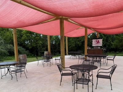 Outdoor seating area with metal tables and chairs under pink shade cloth.