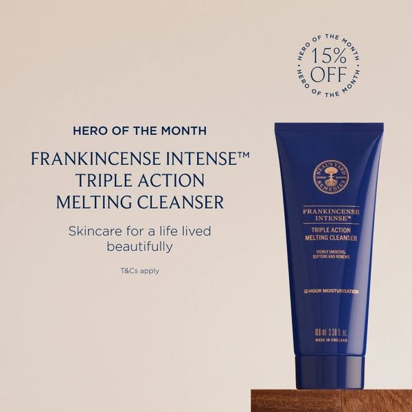 navy blue tube of product with gold writing standing on small wooden  ledge