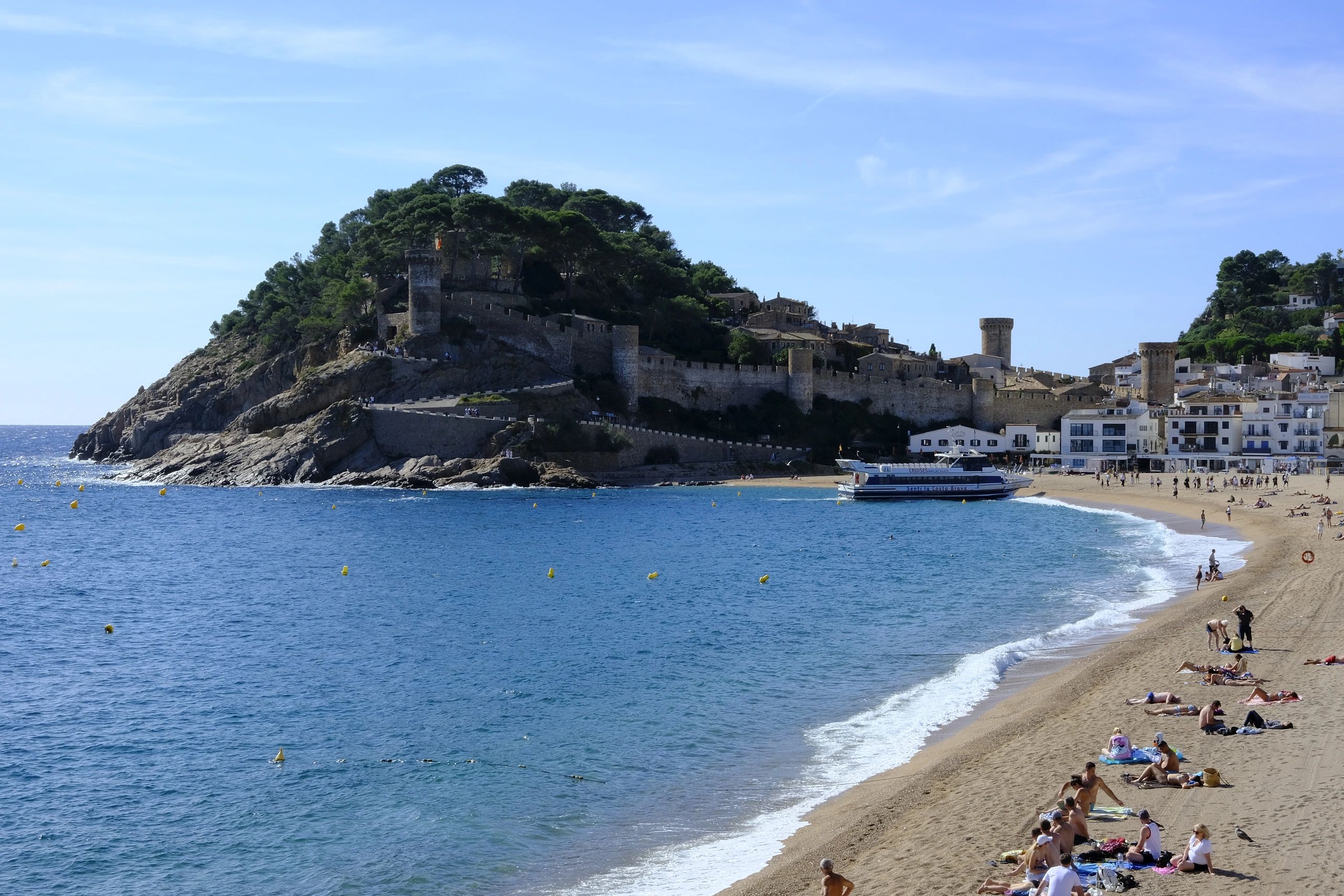 Historic coastal town with a beach and castle walls.