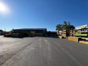 Outdoor lumber yard with stacks of wood and clear blue sky.