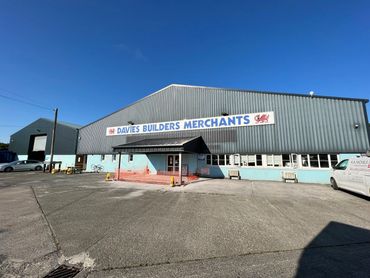 Exterior view of Davies Builders Merchants warehouse under clear blue sky.