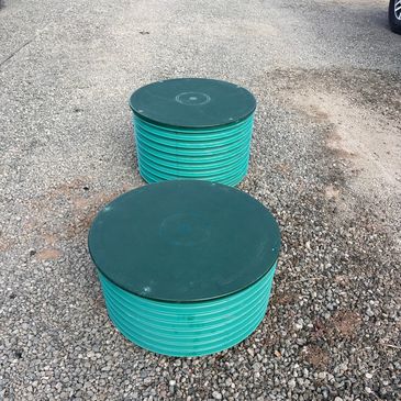 Two green underground utility boxes on gravel.