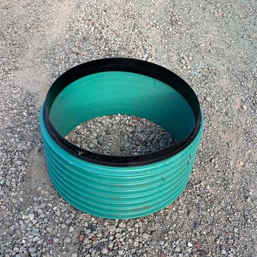 Teal plastic corrugated pipe on gravel.