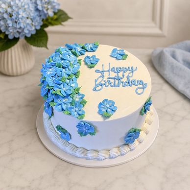 Round birthday cake decorated with blue flowers and "Happy Birthday" text.