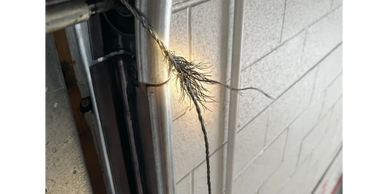 Frayed metal wire sparking near a garage door mechanism.