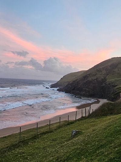 Sunset over a peaceful beach with blue lounge chairs and a wooden house.