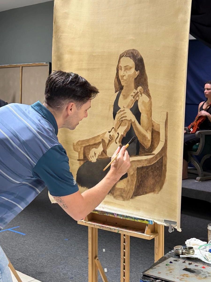 Artist painting a portrait of a woman with a violin.
