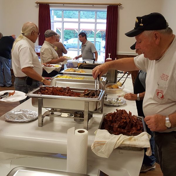 People serving food at a buffet in a community setting.