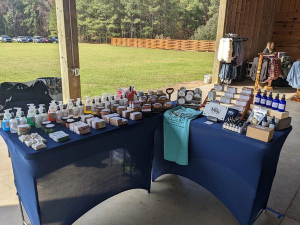 Outdoor market table displaying handmade soaps and lotions neatly arranged.