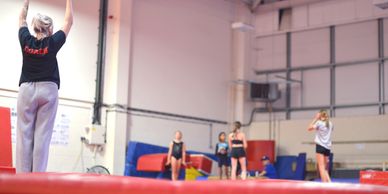 Gymnastics coach instructing young gymnasts in a gym.