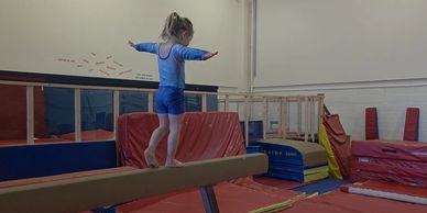 Young girl balancing on a gymnastics beam.