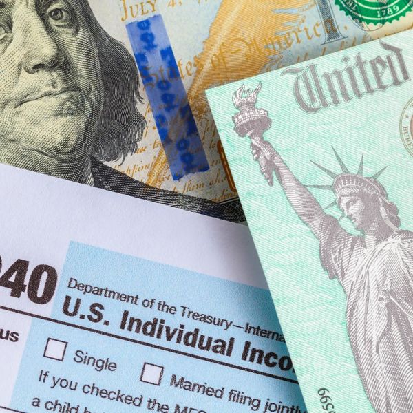 Close-up of a US tax form, a stimulus check, and part of a $100 bill.
