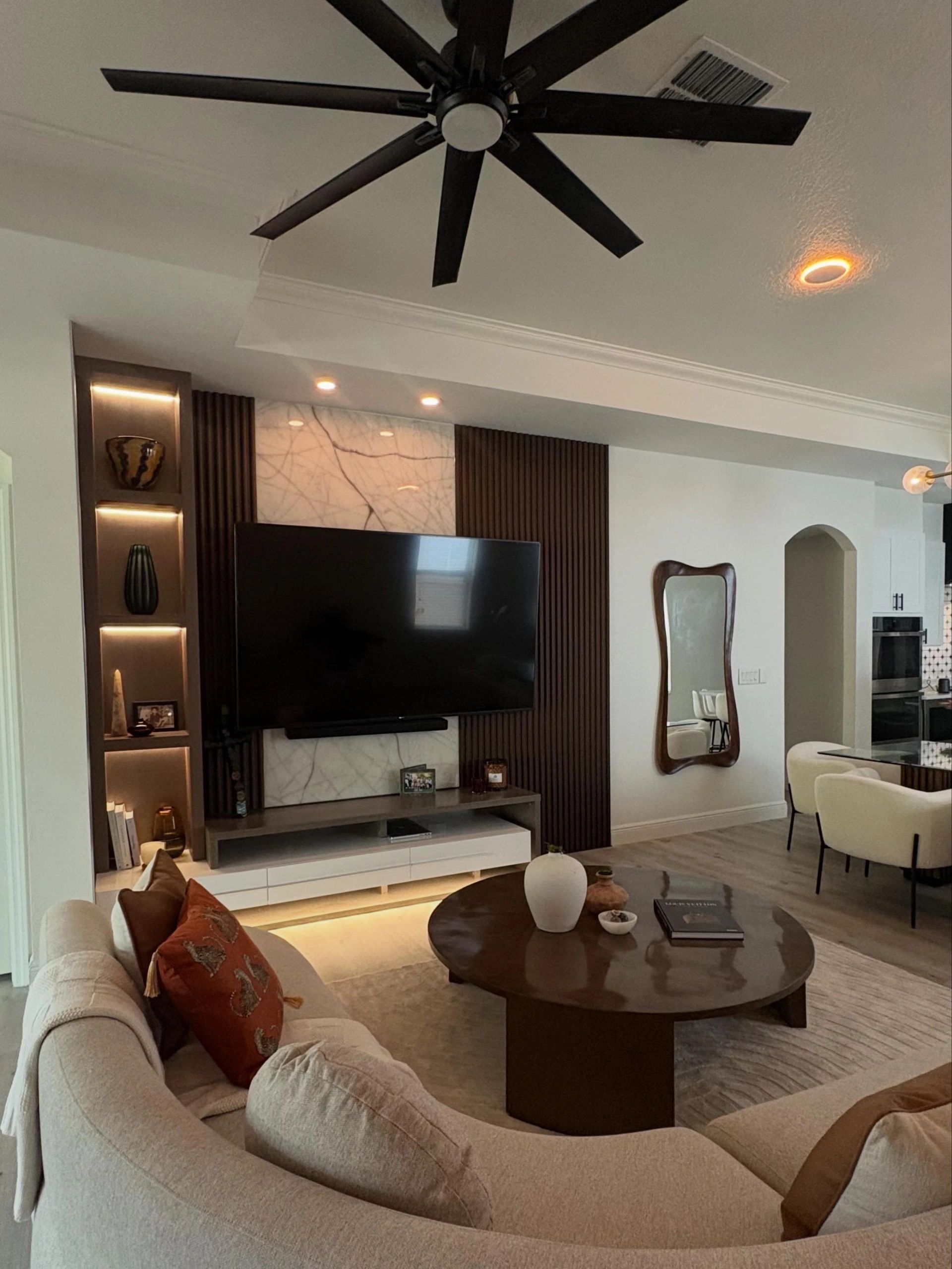 Modern living room with curved sofa, wooden coffee table, and sleek TV setup.
