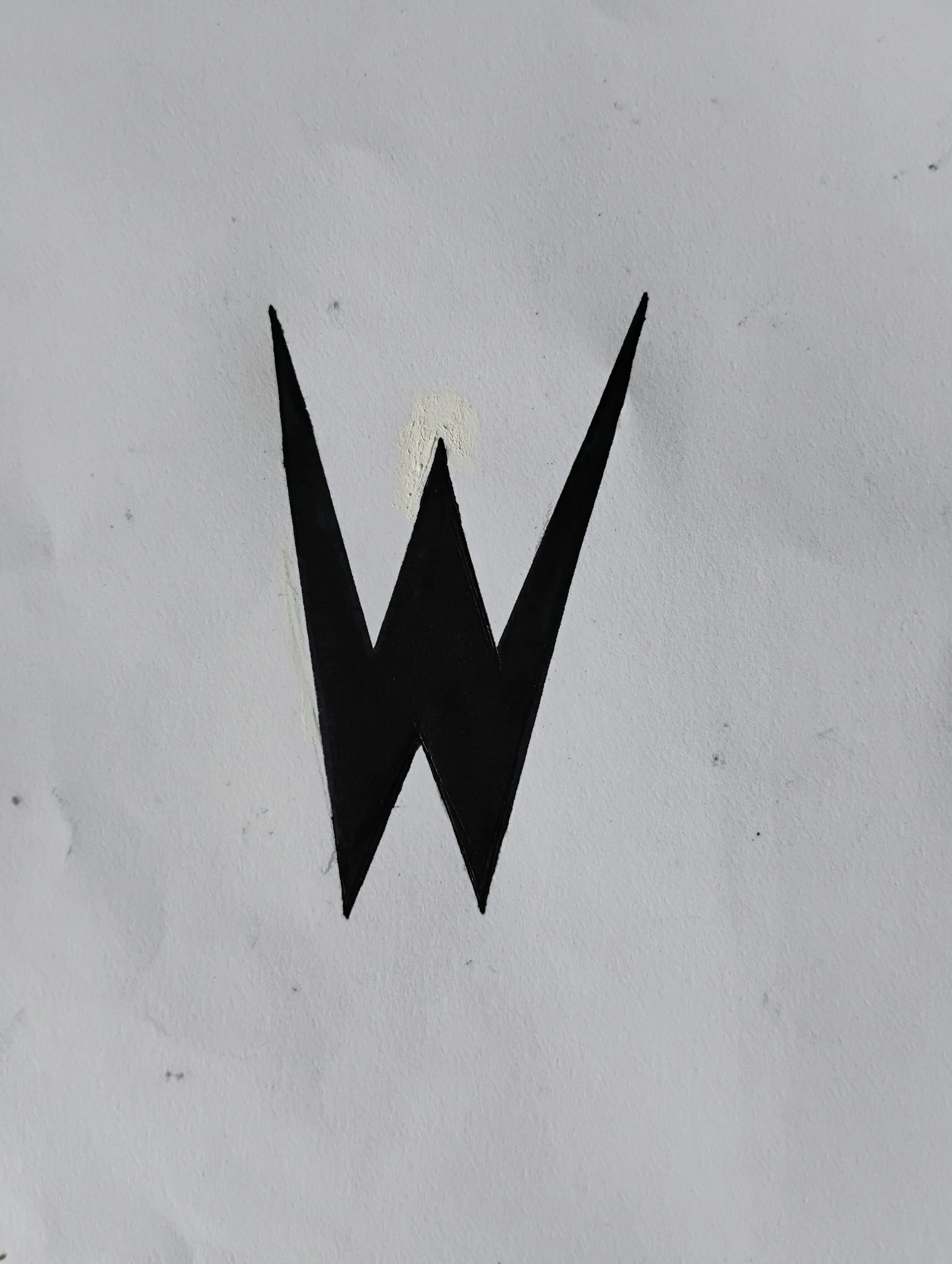 Black letter W painted on a white wall.