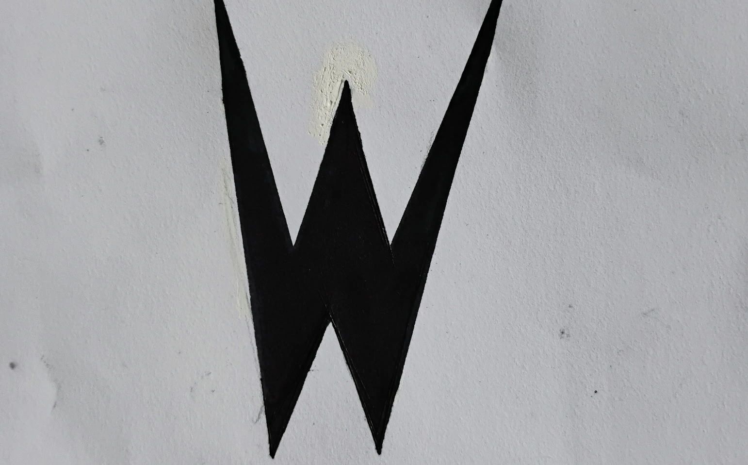 Black letter W painted on a white wall.