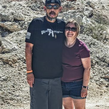 A couple smiling outdoors against a rocky background.