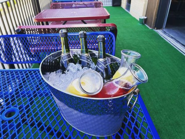 3 bottles of Champagne and 3 juice jugs in an ice bucket set on the patio